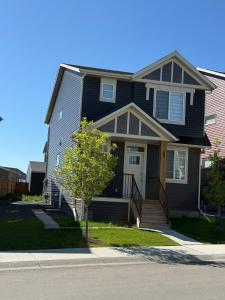 a black house with a tree in front of it at Cozy Suite Near Airport in YYC