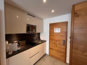 a kitchen with a sink and a wooden door at Alpine Apartment Andermatt in Andermatt
