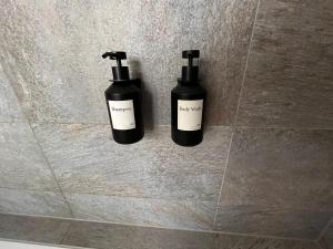two bottles ofodorizers on the wall of a bathroom at Alpine Apartment Andermatt in Andermatt