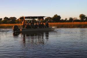 a group of people in a small boat on the water at The Bell Frog Inn in Maun