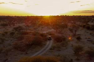 a bus driving down a road in the desert at The Bell Frog Inn in Maun