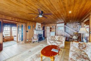 a living room with a ceiling fan and a table at Dog-friendly, bayfront home - gorgeous ocean views, private balcony & fireplace in East Boothbay