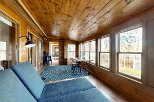 a living room with a couch and a table and windows at Gorgeous Waterfront Home on Westport Island with 2 Sunrooms in Montsweag