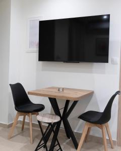a table with two chairs and a television on a wall at Akrolithos apartments ground floor in Platy