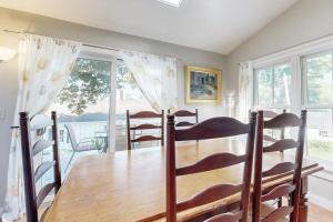 a dining room with a wooden table and some windows at Beautiful Retreat | Home Office | Walk 5 MInutes to Main Street in Wiscasset
