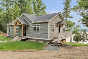 a small grey house with a porch and a porch at Elegant lakefront home near Bar Harbor & Acadia with modern kitchen, lake views in Orland