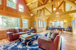 a living room with couches and a table in a cabin at Tranquil Haven | Secluded waterfront house with sauna, dock, kayaks, canoe, gym in Greenville