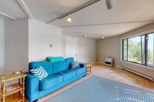 a living room with a blue couch and a window at Unique oceanfront home with a deck, tons of natural light, & amazing views in Wiscasset