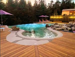 a swimming pool with a deck and a wooden floor at Logis Clair Matin Resort & Spa in Le Chambon-sur-Lignon