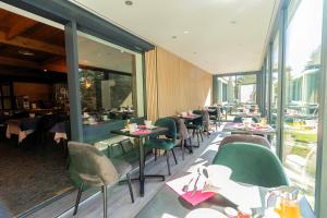 a restaurant with green chairs and tables and windows at Logis Clair Matin Resort & Spa in Le Chambon-sur-Lignon