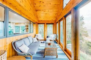 a screened in porch with a couch and chairs at Renovated oceanfront home with stunning view & pebbly beach - snowbird-friendly in Saint George