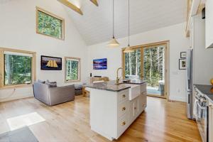 a kitchen and living room with white walls and wood floors at Charming New Home with Hot Tub, Spacious Deck, Gas Grill, WiFi, and Washer/Dryer in Boothbay