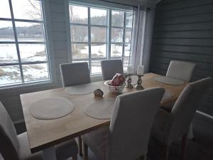 ein Esstisch mit Stühlen und ein Holztisch und Fenster in der Unterkunft T - Stua in Moen i Målselv
