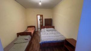 two beds in a small room with wooden floors at Гостевой дом Арай in Bosteri