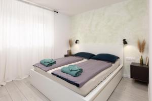 a white bedroom with a large bed with blue pillows at Timber Fairies in Slunj +35 photos