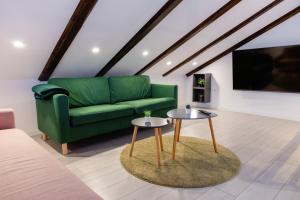 a living room with a green couch and two tables at Timber Fairies in Slunj