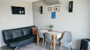 a living room with a couch and a table and chairs at ''Ābeļdārza māja'' in Āboliņi