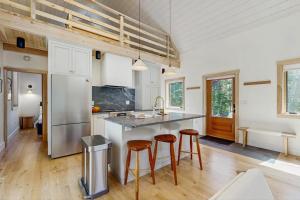 a kitchen with a counter and stools in a room at Charming New Home with Hot Tub, Spacious Deck, Gas Grill, WiFi, and Washer/Dryer in Boothbay +19 photos