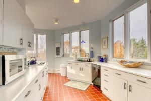 a large kitchen with white cabinets and a red tile floor at Bayfront home with 270-degree views, large deck & porch - near Popham Beach in Phippsburg +45 photos
