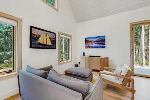 a living room with a couch and chairs and windows at Charming New Home with Hot Tub, Spacious Deck, Gas Grill, WiFi, and Washer/Dryer in Boothbay
