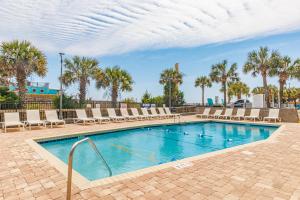 a swimming pool with lounge chairs and palm trees at Coastal Modern Oceanfront 2BR Yachtsman S506 in Myrtle Beach