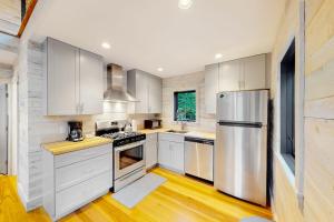 a kitchen with white cabinets and a stainless steel refrigerator at Contemporary retreat with grill, firepit, & patio - walk to beach in Marlboro +15 photos