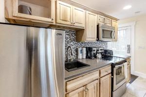 a kitchen with wooden cabinets and a stainless steel refrigerator at New Riverfront Condo in Sheepscot Harbour - Walk to Famed Seafood Eatery in Edgecomb