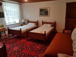 two beds in a room with a red rug at AmedaPm in Gjirokastër