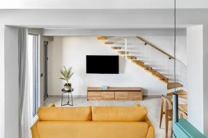 a living room with a yellow couch and a tv at Merivian Seaside Suites in Kanali