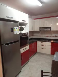 a kitchen with red cabinets and a stainless steel refrigerator at Duplex pres de la mer a Alger in Rouiba