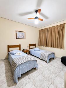 a bedroom with two beds and a ceiling fan at Hotel São Lucas in Alfenas +24 photos