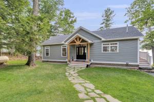 a gray house with a porch and a grass yard at Elegant lakefront home near Bar Harbor & Acadia with modern kitchen, lake views in Orland +42 photos