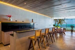 a bar with wooden chairs in a room with the ocean at Luxury Beachfront 4BR PH in Bahia Soliman in Balcheil