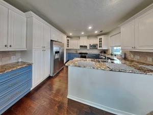 a large kitchen with white cabinets and a large island at West Bay Getaway in Galveston +23 photos