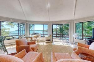 a living room with chairs and a table and windows at Unique oceanfront home with a deck, tons of natural light, & amazing views in Wiscasset