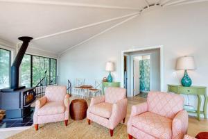 a living room with two chairs and a fireplace at Unique oceanfront home with a deck, tons of natural light, & amazing views in Wiscasset