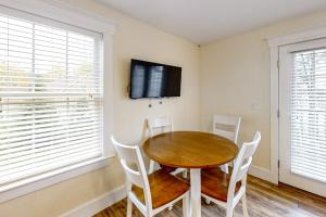 a dining room with a wooden table and white chairs at New Riverfront Condo in Sheepscot Harbour - Walk to Famed Seafood Eatery in Edgecomb