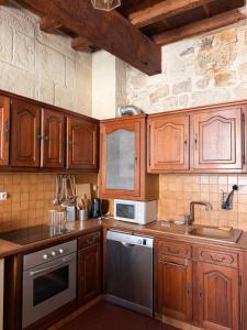 a kitchen with wooden cabinets and stainless steel appliances at Les chambres de Pierre in Arles