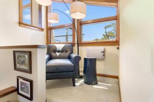 a living room with a chair and large windows at Elegant ocean view home with breathtaking views, private hot tub & large deck in Rockport