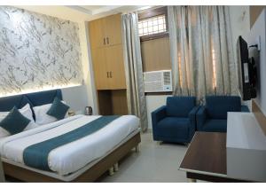 a bedroom with a bed and two blue chairs at Shree Sanmat Guest House in Gwalior