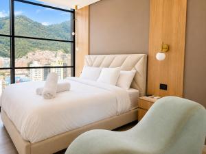 a bedroom with a bed with a chair and a window at Apartaestudio Centro Internacional UTEK in Bogotá