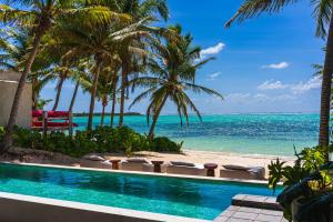 a swimming pool next to a beach with palm trees at Luxury Beachfront 3BR Apt 102 | Neea Bahia Soliman in Balcheil