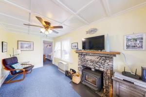 a living room with a fireplace and a flat screen tv at Dog-friendly Fisher Hill home with patio and wood stove - walk to the harbor in Boothbay Harbor