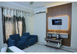 a room with two blue chairs and a flat screen tv at Shree Sanmat Guest House in Gwalior +24 photos