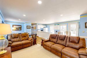 a living room with two leather couches and a kitchen at Colorful duplex home with a large yard, deck, WiFi, & ideal Midcoast location in Boothbay