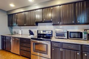 a kitchen with stainless steel appliances and wooden cabinets at Tree-lined home with screened porch & perfect Midcoast location in Damariscotta