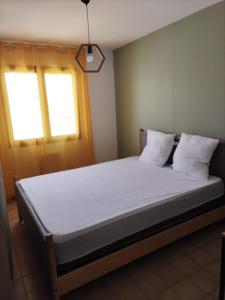 a bedroom with a bed with white sheets and a window at Maison 80 m2 - proche des plages in Montpellier