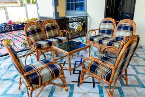 a group of four rattan chairs and a table at Edmundson Villa Apartment in Ejisu