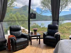 two chairs and a bed in a room with a view at Lofoten Aurora Dome in Hanøya