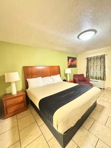 a bedroom with a large bed and a chair at Texas Inn Beaumont in Beaumont